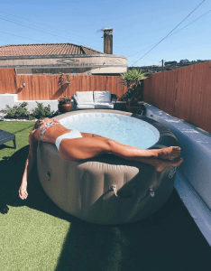 A woman lying on the side of an inflatable hot tub for relaxation