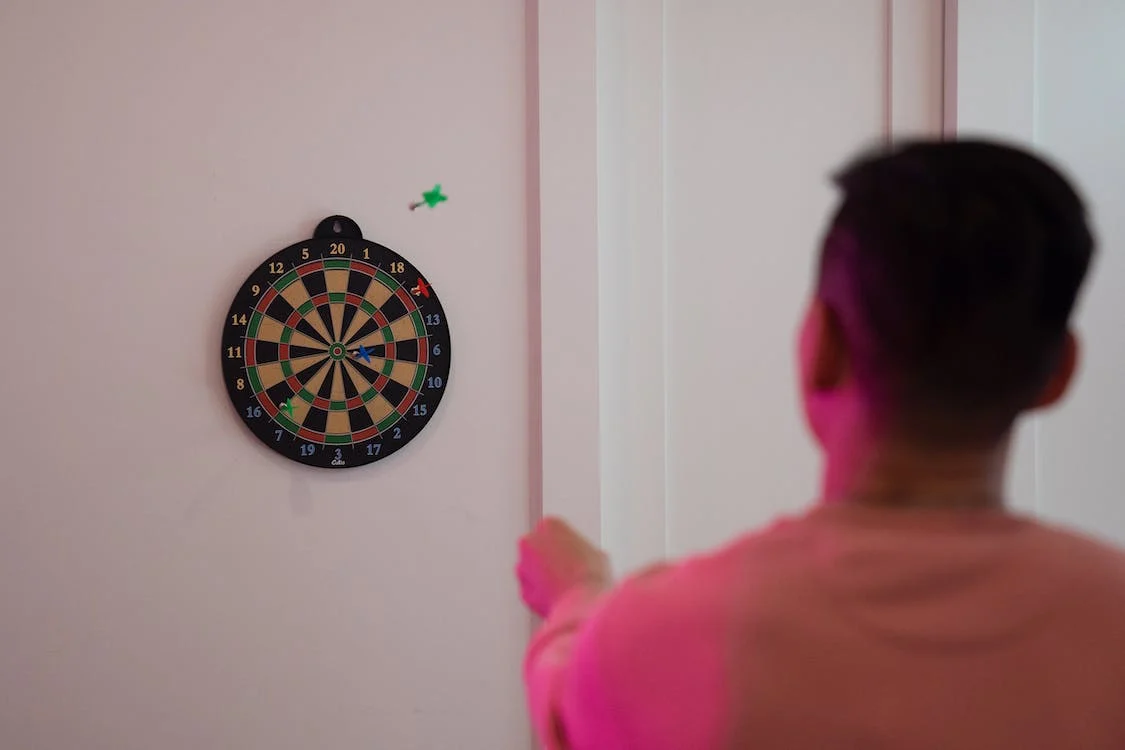 A person throwing a dart in mid-air at the dartboard