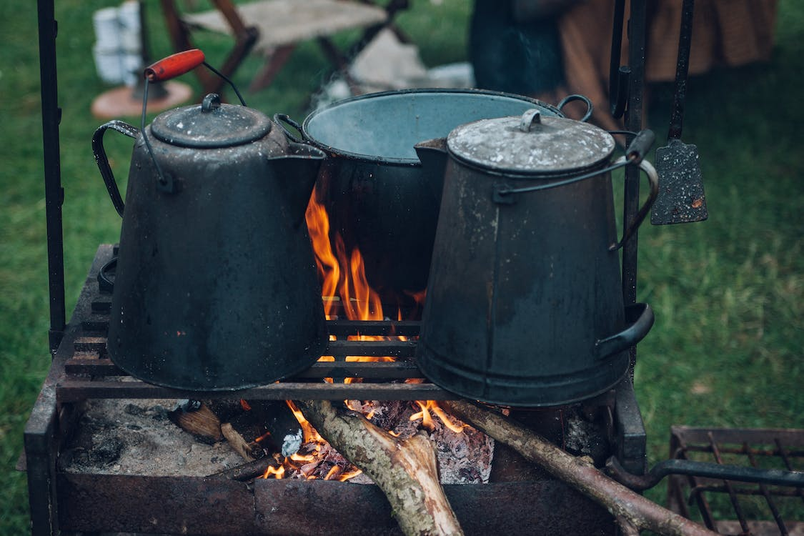 Saucepan and kettles on a lit natural gas grill 