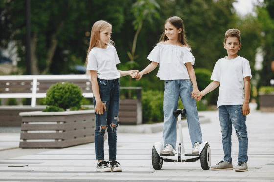 A young kid is learning to hoverboard with their friends